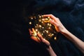 Hands holding Christmas lights in the dark