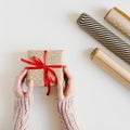 Hands holding Christmas present wrapped in polka dot kraft paper with red ribbon Royalty Free Stock Photo