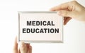 Hands holding clipboard with text medical education on a sheet of paper