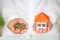 Hands holding coins and a house model,  Housing industry mortgage plan and residential tax saving strategy, mortgage, investment, Royalty Free Stock Photo