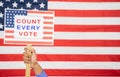 Hands Holding Count every vote sign board with US Flag as Background with copy space - Concept of voter rights and US