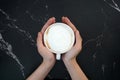 Hands holding a cup of coffee, with black marble background Royalty Free Stock Photo