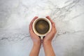 Hands holding a cup of coffee, with marble background Royalty Free Stock Photo