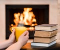 Hands holding cup of coffee near the fireplace