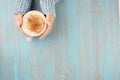 Hands holding cup of hot chocolate, blue wooden table, blue cozy sweater, beautiful pink manicure, home style, winter morning,