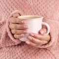 Hands holding cup of tea or coffee, pink home cozy jacket, beautiful pink manicure, home style, autumn morning, close up Royalty Free Stock Photo