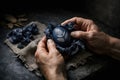 Hands holding dark blue Easter egg decorated with natural fern leaf pattern. Moody and rustic atmosphere with dark background Royalty Free Stock Photo