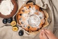 Hands holding decorating plum pie with sugar powder icing. Making original Famous plum torte, fruit cake. Royalty Free Stock Photo