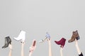 Hands holding different woman shoes on grey background.