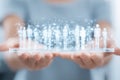 Hands holding a digital hologram of human figures connected by network lines on a transparent tablet Royalty Free Stock Photo