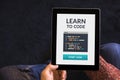 Hands holding tablet with learn to code concept on screen Royalty Free Stock Photo