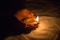 Hands holding diwali diya or indian traditional oil lamp made of clay with glowing flame during festival celebration. dark Royalty Free Stock Photo