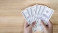 Hands holding 100 dollar bills. Women's hand holds a fan of dollars on wooden table Royalty Free Stock Photo