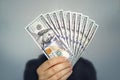 1000 dollars in 100 bills in a man`s hand close-up on a dark background. Hands holding dollar cash