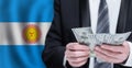 Hands holding dollar money on flag of Argentina