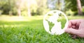 Hands holding earth made from paper over green grass background. Royalty Free Stock Photo