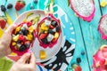 Hands holding and eating from a dragon fruit salad bowl. Royalty Free Stock Photo