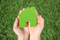 Hands holding eco house icon concept on the green grass background Royalty Free Stock Photo