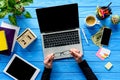 hands holding eyeglasses by laptop on blue wooden table with stationery Royalty Free Stock Photo