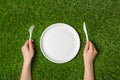 Hands holding fork and knife with plate on grass Royalty Free Stock Photo