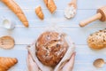 Hands holding fresh bread on the blue wooden background top view