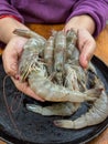 hands holding fresh raw prawns over black frying pan Royalty Free Stock Photo