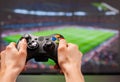 Hands holding the game controller while man playing game on TV Royalty Free Stock Photo