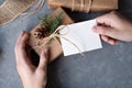 Hands holding gift box and blank paper card mockup on gray table background. Christmas sustainable ecological business Royalty Free Stock Photo