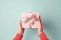 Hands holding gift box with Christmas design on light pastel background. Christmas and Valentine\'s Day concept