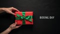 Hands holding gift box with green ribbon on Boxing Day, festive seasonal holiday banner