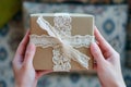 hands holding a gift box with a magnified focus on the intricate lace ribbon
