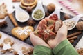 Hands holding gingerbread cookies decorated with natural seeds and dried berries - holiday sweets Royalty Free Stock Photo