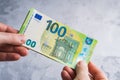 Hands holding and giving one hundred euro banknotes. Stack of money in man hands on gray background Royalty Free Stock Photo