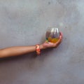 hands holding a glass containing colorful balls