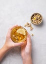 Hands holding a glass cup with chamomile herbal tea on a light background with dry flowers. The concept of a healthy drink for Royalty Free Stock Photo