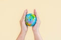 Hands are holding the globe with yellow background. The concept of saving the world and caring for the world