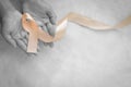 Hands holding gold ribbon on white fabric background with copy space. The international awareness symbol for Childhood Cancer. Royalty Free Stock Photo