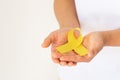 Hands holding gold ribbon on white isolated background with copy space. The international awareness symbol for Childhood Cancer. Royalty Free Stock Photo