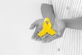 Hands holding gold ribbon on white  background with copy space. The international awareness symbol for Childhood Cancer. Royalty Free Stock Photo