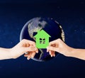 Hands holding green house over earth in space Royalty Free Stock Photo