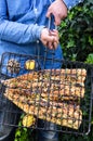 Hands holding a grill containing a barbequed fish