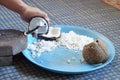 Hands holding a half-cut coconut to scrape