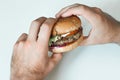 Hands holding a hamburger, on white background