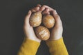 Hands holding hand painted easter eggs on black rustic metallic background, top view shot Royalty Free Stock Photo