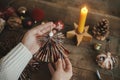 Hands holding handmade christmas angel from festive red wrapping paper on background of rustic wooden table with paper stars, Royalty Free Stock Photo