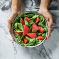Hands holding healthy fresh summer watermelon salad with arugula, spinach and greens on light marble background. Healthy food, Royalty Free Stock Photo