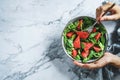 Hands holding healthy fresh summer watermelon salad with arugula, spinach and greens on light marble background. Healthy food, Royalty Free Stock Photo