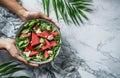Hands holding healthy fresh summer watermelon salad with arugula, spinach and greens on light marble background with tropical Royalty Free Stock Photo