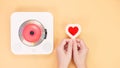 Hands holding heart shape red gift card next to white cd player with red disc on yellow background. Love music, Valentine day, Royalty Free Stock Photo