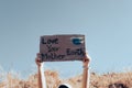 Hands holding holding poster with words Love your Mother Earth against the background of blue sky. climate change concept Royalty Free Stock Photo